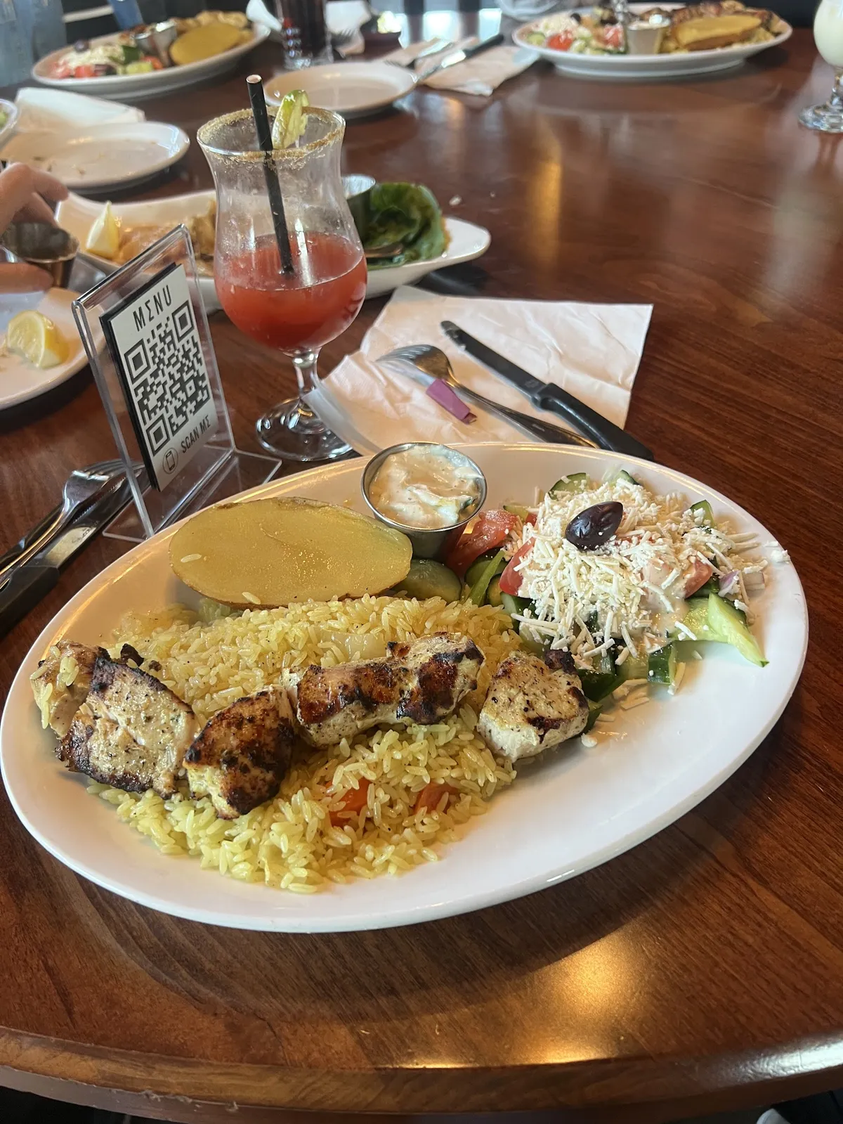 Plate of chicken skewers, rice, salad, and potato