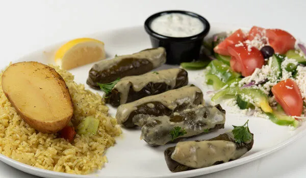 Plate of dolmades, rice, potato, and Greek salad